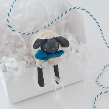 Load image into Gallery viewer, A miniature spun cotton sheep hanging out of a white gift box in white tissue shredding against a white background. Pic 4 of 8. 
