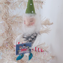 Load image into Gallery viewer, A vintage style spun cotton pine cone elf sitting on a candy cane, hanging from a white Christmas tree. Pic 2 of 10. 
