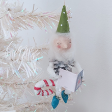 Load image into Gallery viewer, Another view of the spun cotton pine cone elf sitting on a candy cane, hanging on a white Christmas tree. Pic 3 of 10. 
