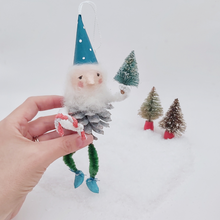 Load image into Gallery viewer, Vintage style spun cotton pine cone elf, held in hand against a white background. Two miniature vintage bottle brush trees are in the distance. Pic 3 of 7.
