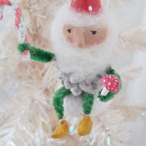 Close up of face and red spun cotton mushroom held by vintage style spun cotton pine cone elf, hanging from white Christmas tree. Pic 1 of 9.