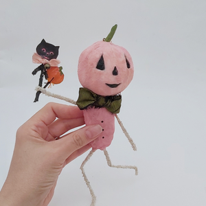 Vintage style spun cotton pink jack-o'-lantern man held in hand against white background. Pic 2 of 10.