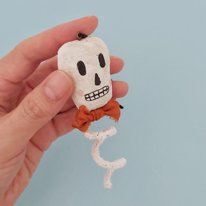 A vintage style spun cotton skeleton ornament held in hand against a light blue background. Pic 2 of 6.