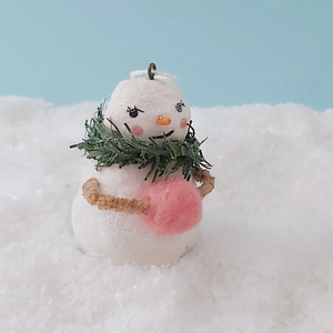 Front view of vintage style spun cotton snow lady holding pink hand muff, on fake snow against a light blue background. Pic 8 of 11.