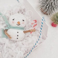Cargar imagen en el visor de la galería, Spun cotton snowman ornament, laying in white gift box with white tissue shredding on a white background. Two bottle brush trees sit next to the box. Pic 6 of 7.
