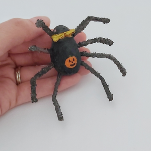 Hand holding spun cotton spider and showing painted jack-o-lantern on his stomach. Pic 4 of 6. 