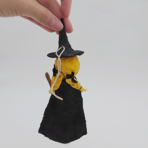 Back view of vintage style spun cotton witch ornament, including black cape and yellow hair in braids held by black bows. Pic 10 of 10. 